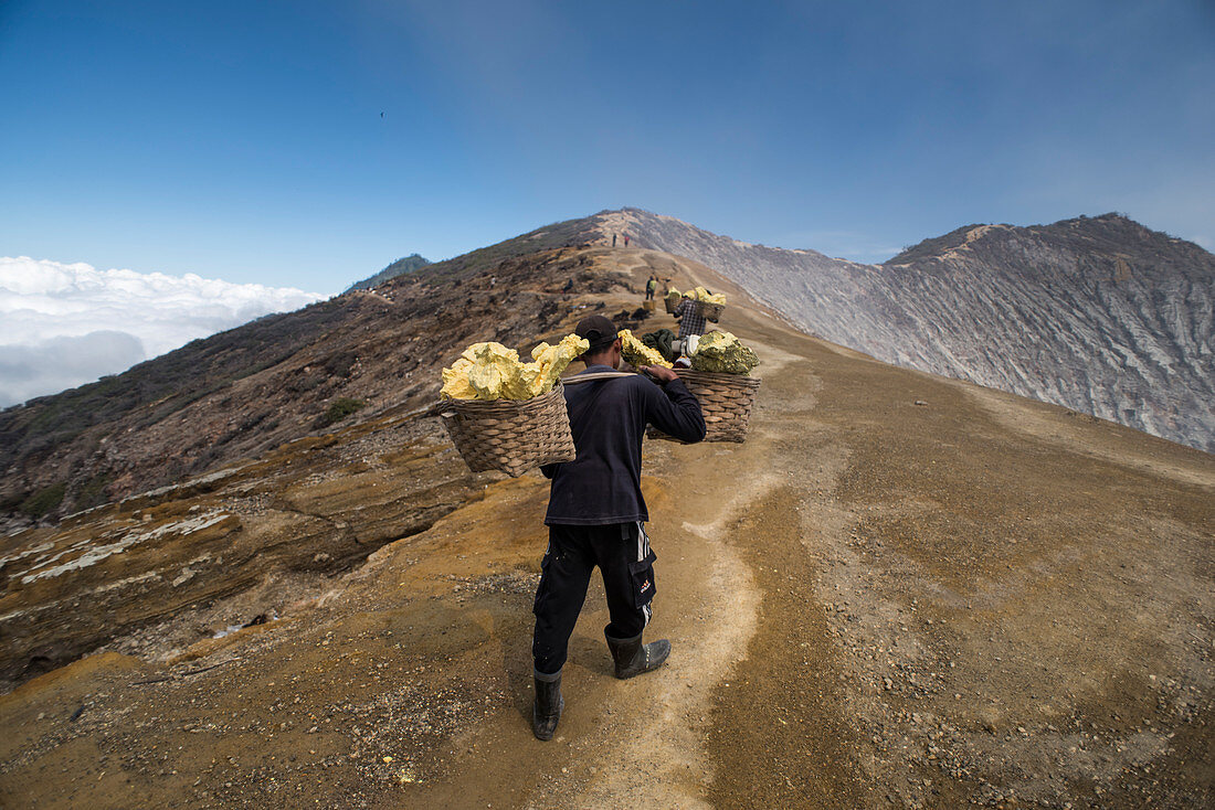 Bergmann trägt schwere Körbe mit Schwefelgesteinen, am Vulkan Kawah Ijen, Ost-Java, Indonesien
