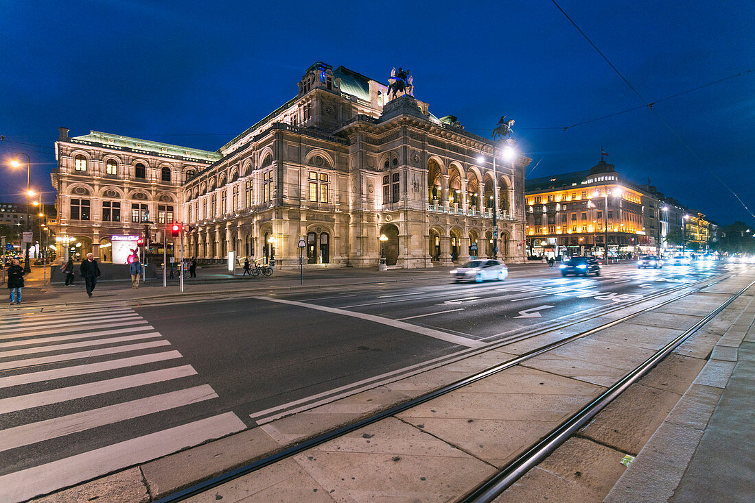 Illuminated exterior of Vienna State Opera across street at night, Vienna, Austria