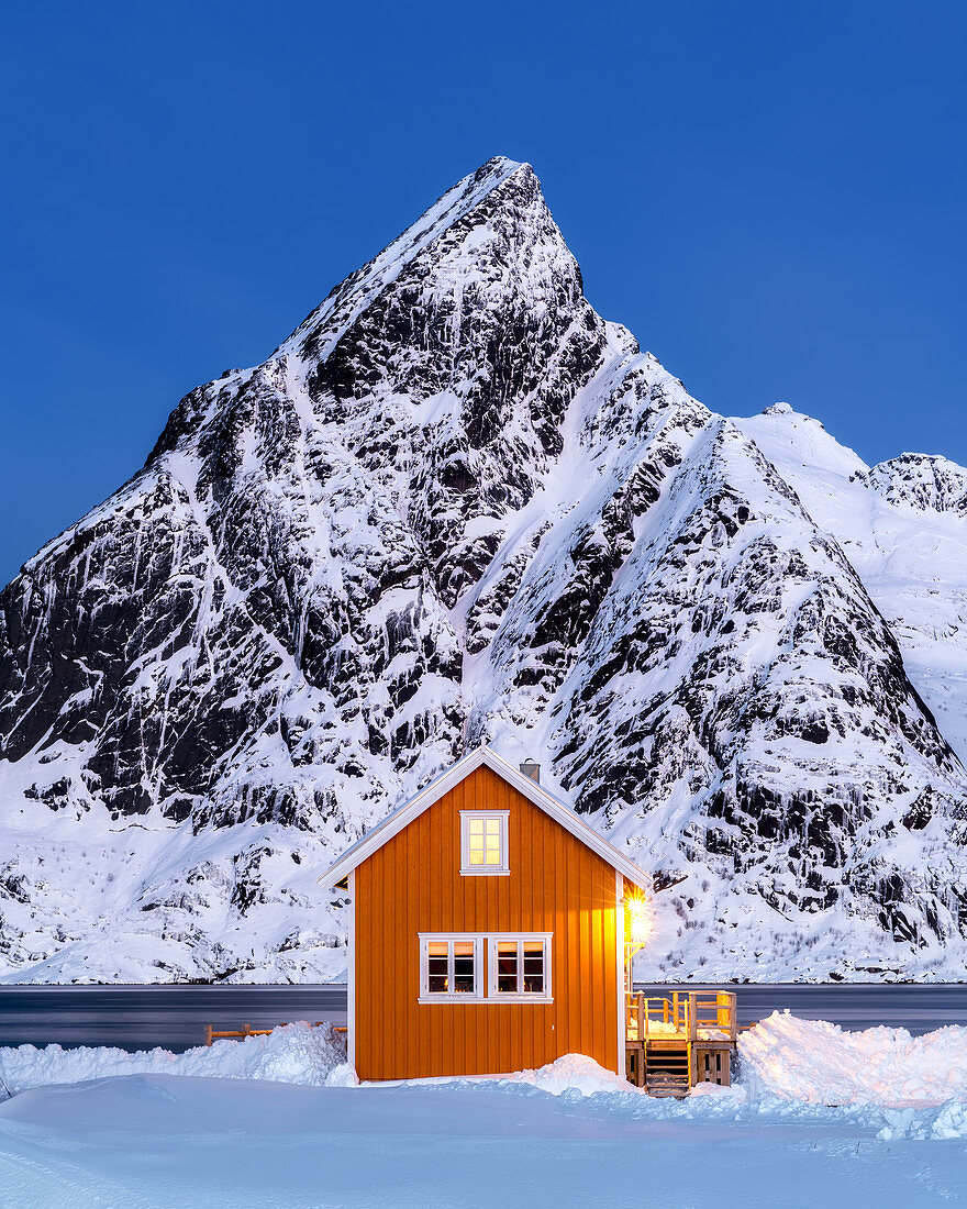 Yellow rorbuer hut in the snow at twilight, Sakrisoy, Moskenesoya, Lofoten Islands, Nordland, Norway, Europe