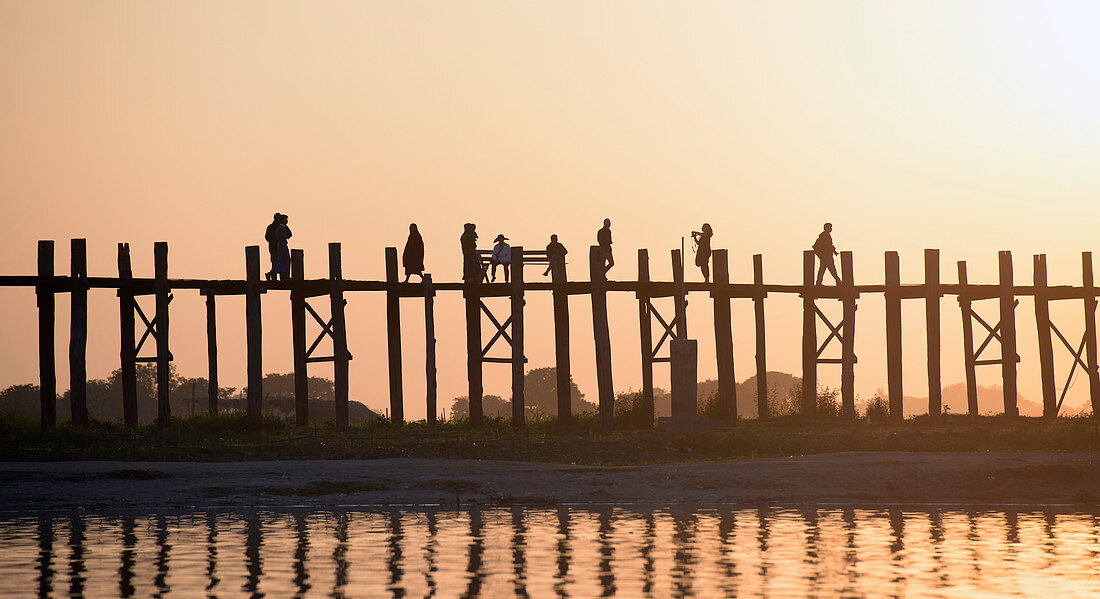 Menschen bei Sonnenuntergang auf erhöhten Holzstegen, Myanmar, Burma