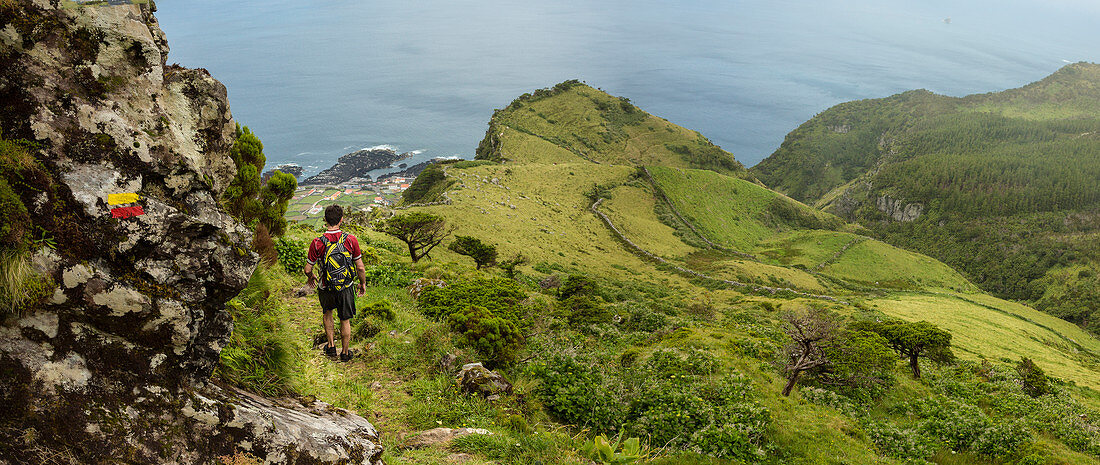 Hiker walking on hilltop path in rural landscape, Azores Islands, Flores, Portugal