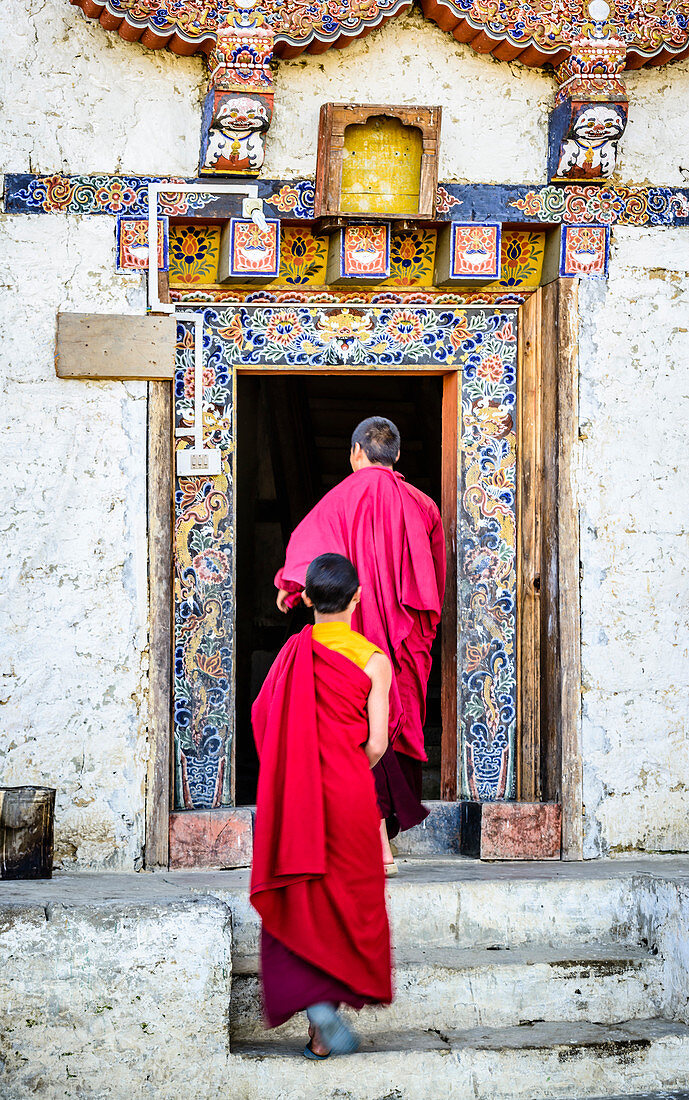 Asian monks walking in temple doorway, Bhutan, Kingdom of Bhutan