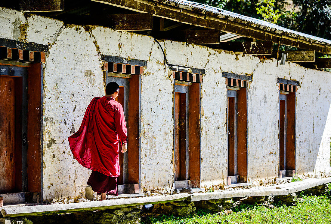 Asian monk walking by monastery doors, Bhutan, Kingdom of Bhutan