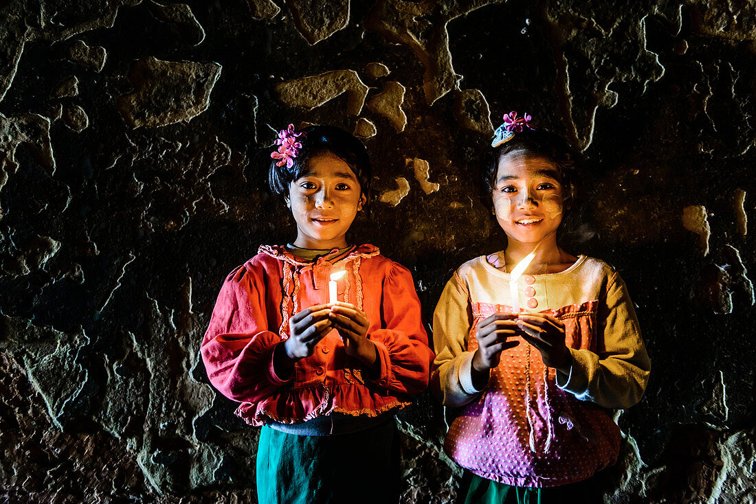 Asian girls holding candles in temple, Myanmar