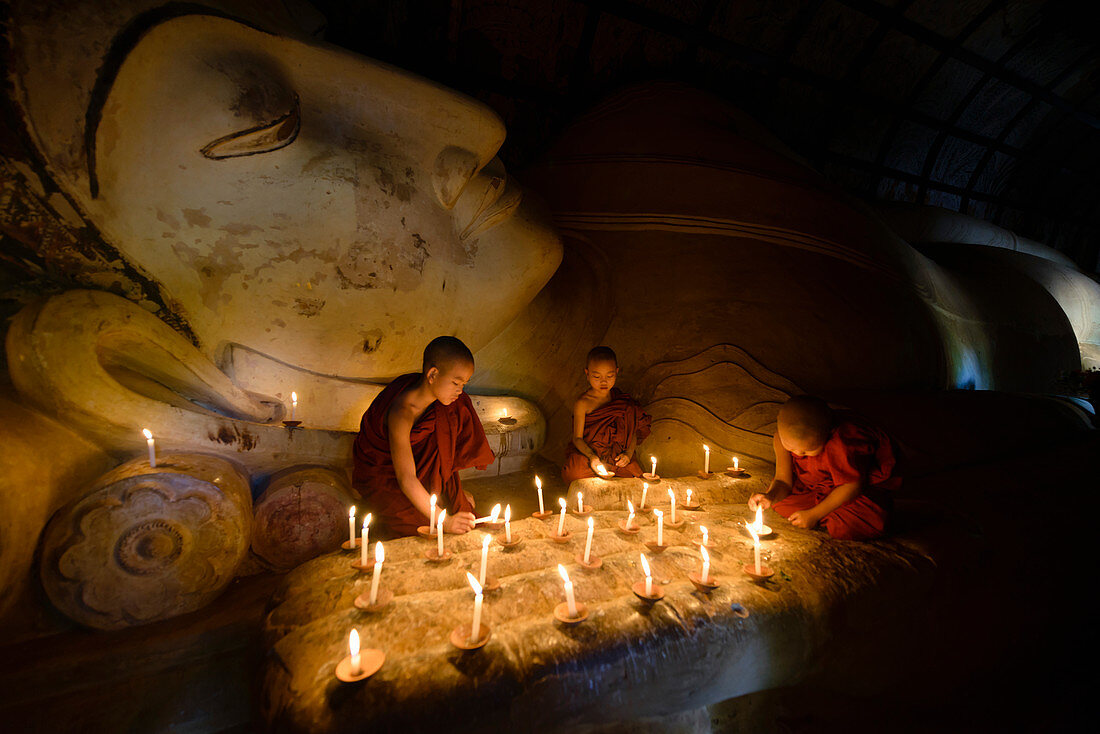 Asiatische Mönche zünden Kerzen im Tempel an, Myanmar