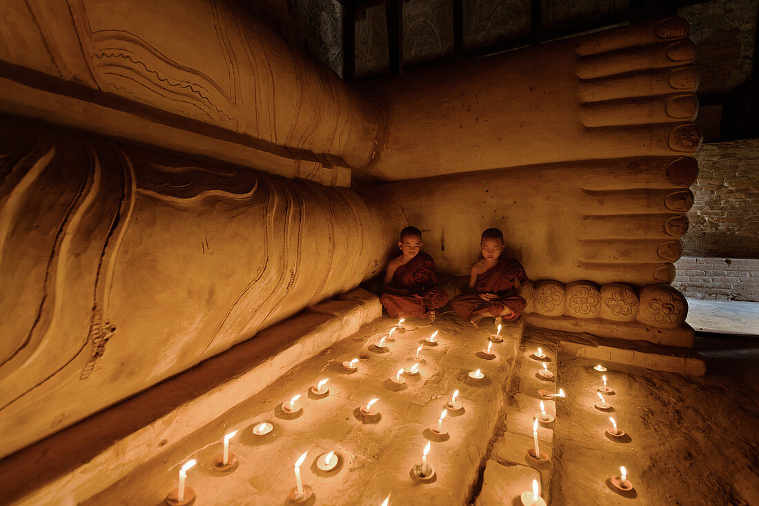 Asian monks lighting candles in temple, Myanmar