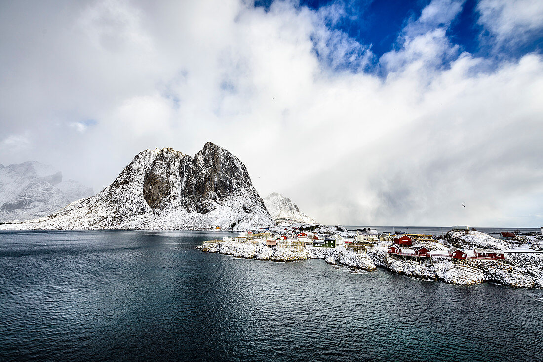 Snowy mountains overlooking rocky coastline, Reine, Lofoten Islands, Norway