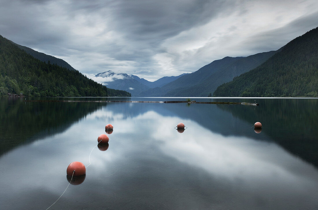 Buoys floating in still remote lake under clouds