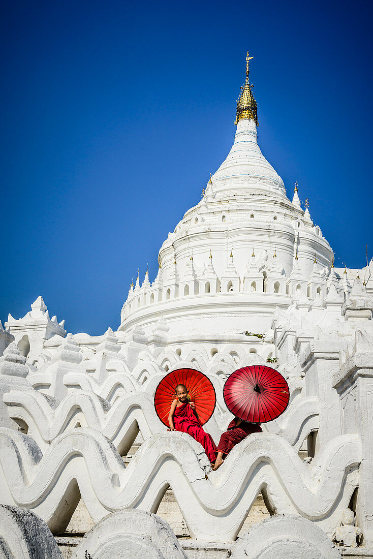 Asian monks sitting under umbrellas at historic temple, Mingun, Mandala, Myanmar