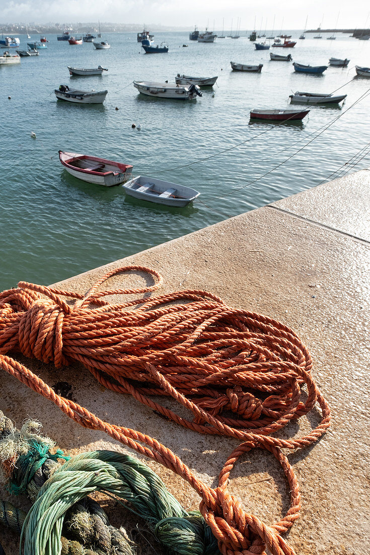 In the foreground ropes, in the background fishing boats in the fishing port of Cascais, Portugal