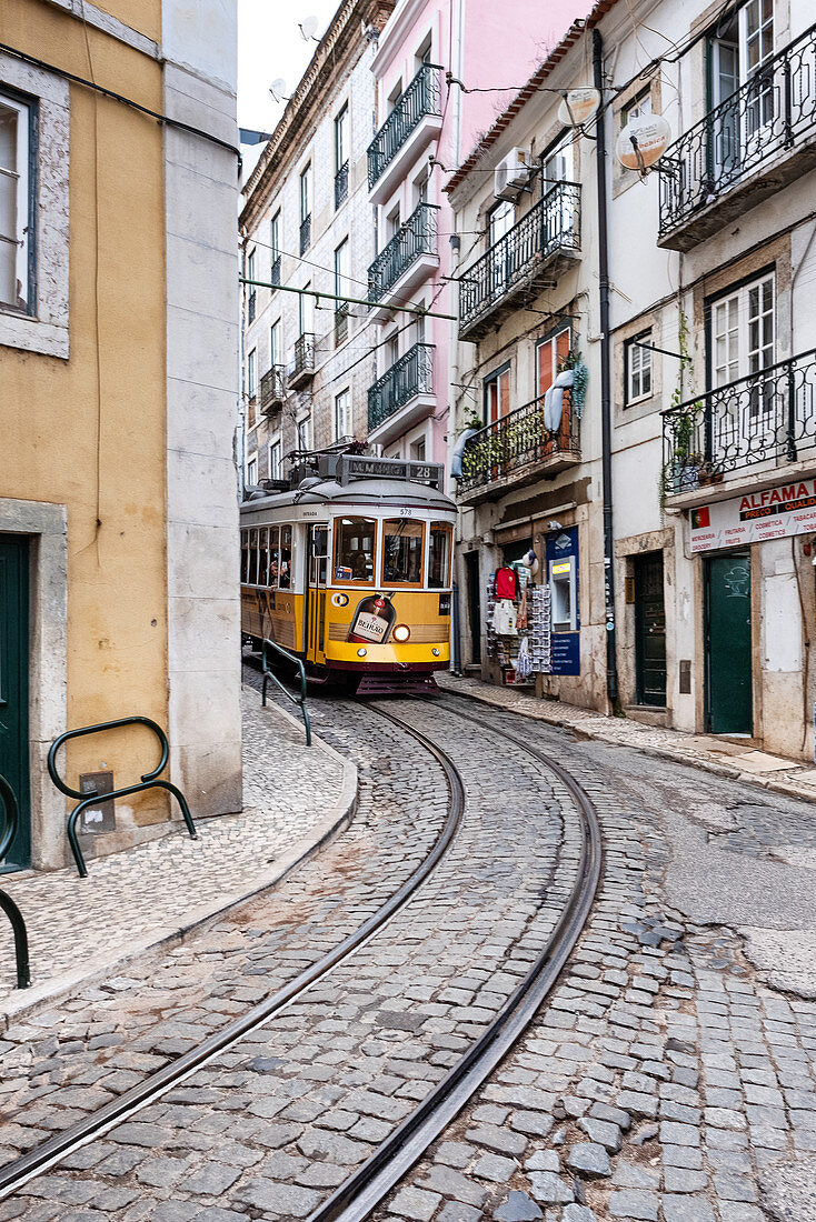 Gelbe Straßenbahn in enger Straße, Alfama, Lissabon, Portugal