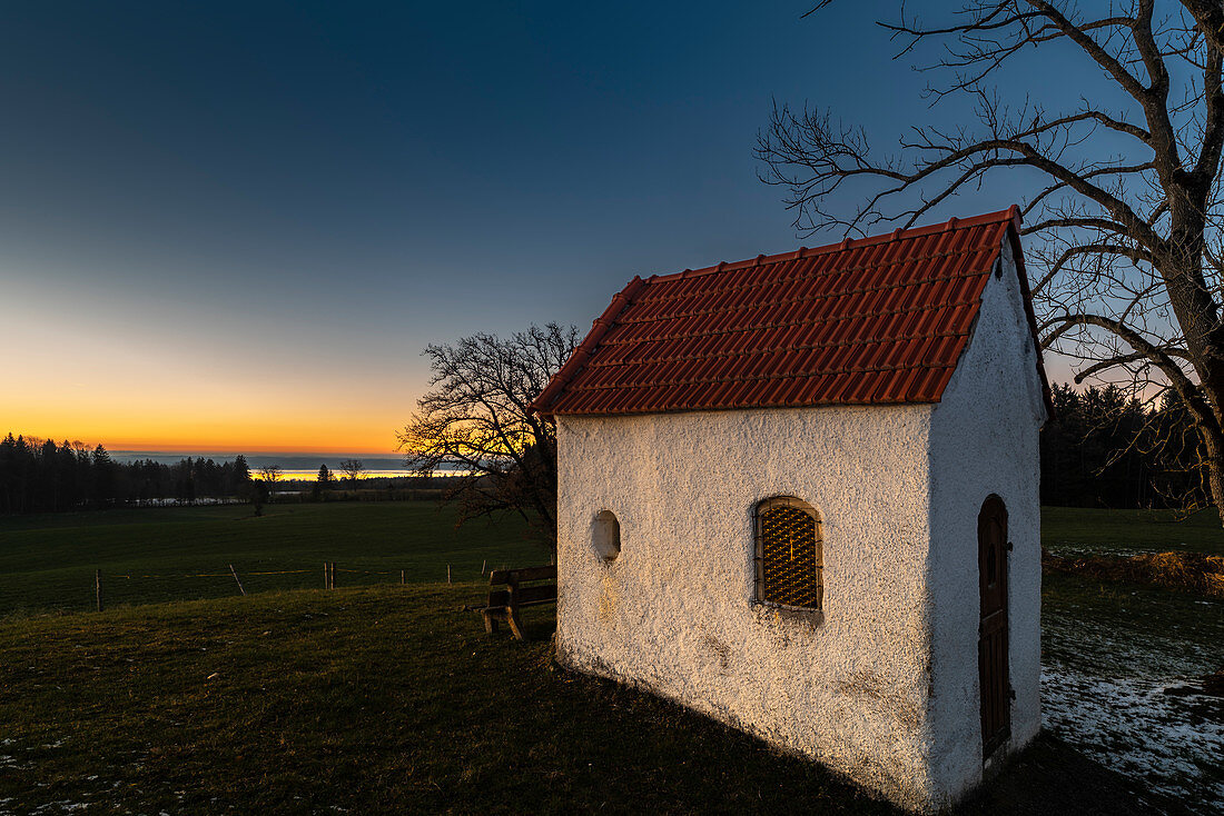 Kleine Kapelle neben einem großen Baum im Gegenlicht am Abend, Seehausen, Starnberger See, Bayern