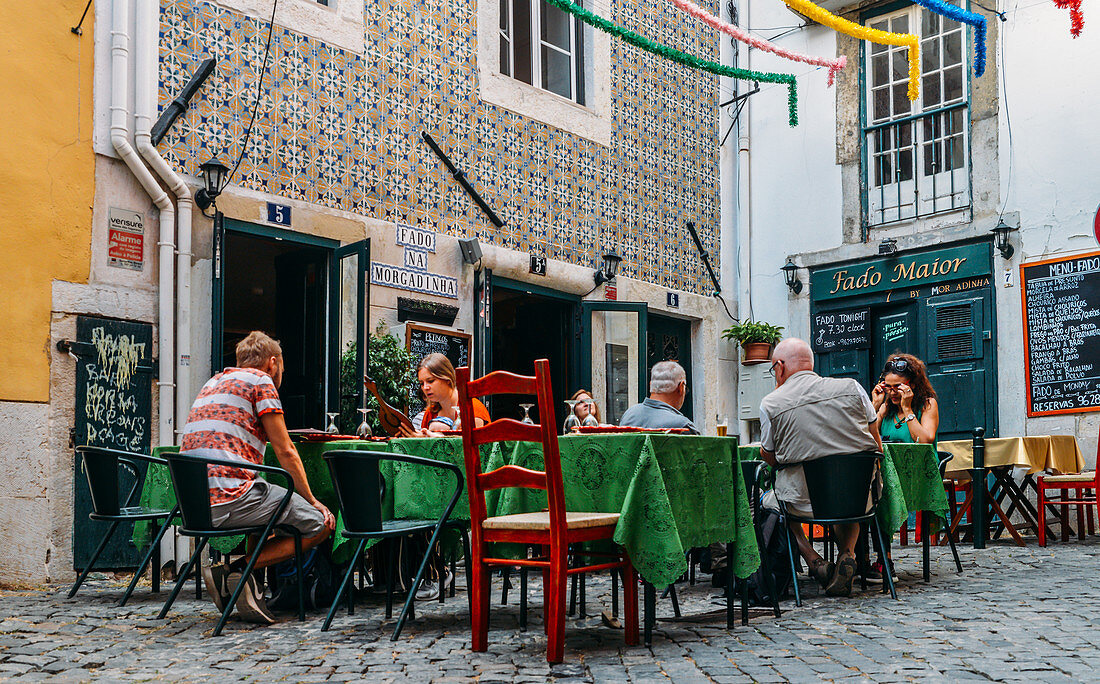 Touristen auf der Terrasse eines Restaurants, das traditionelle portugiesische Gerichte serviert, Alfama, Lissabon, Portugal, Europa