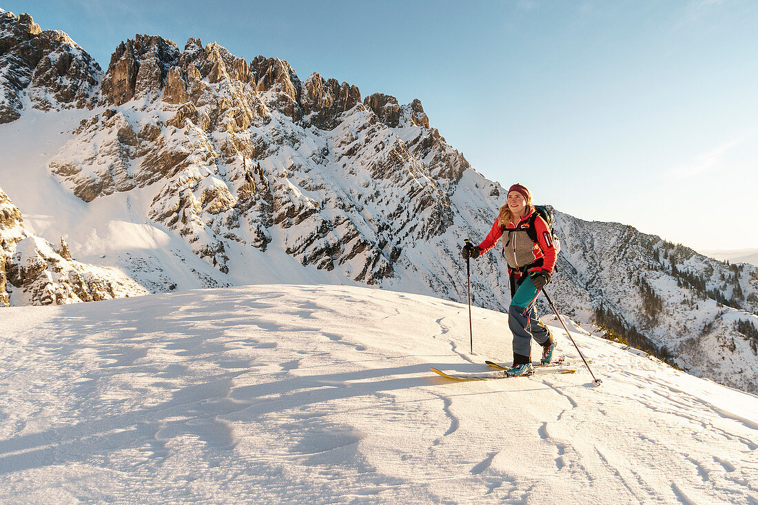 Skitourengeherin steigt in der felsigen Kulisse des Wilden Kaisers im Morgenlicht auf, Gruttenhütte, Tirol, Österreich