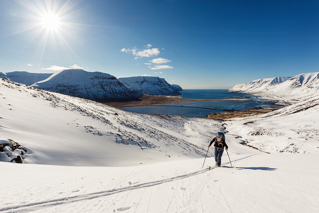 Skitourengeherin im Aufstieg bei bestem Wetter, Westjorde, Island