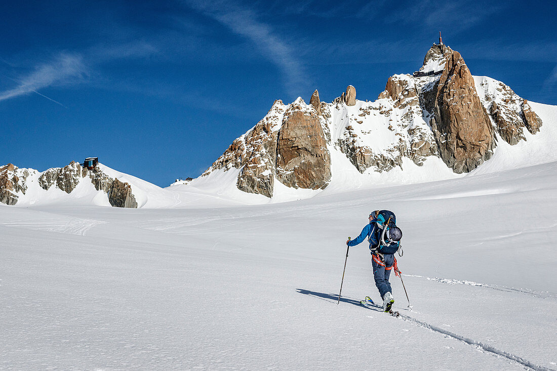 Skitourengeherin im Aufstieg durch das Vallée Blanche mit der Aguille de Cosmiques im Hintergrund, Chamonix, Haute-Savoie, Frankreich
