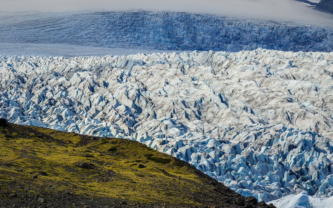 Green hill in front of gigantic glacier break, Jökulsárlón, Iceland