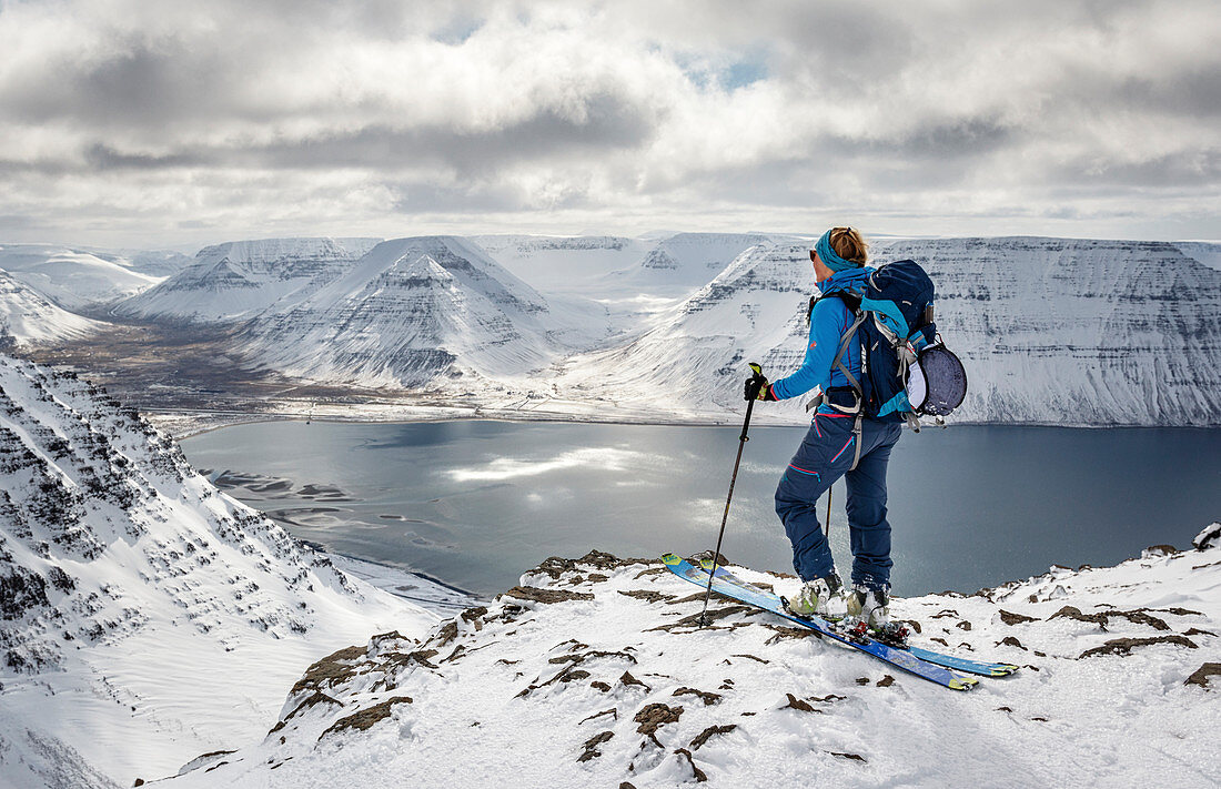 Ski tourer enjoys the view from Hólsfjall on the fjrod landscape of the Westfjords, Iceland