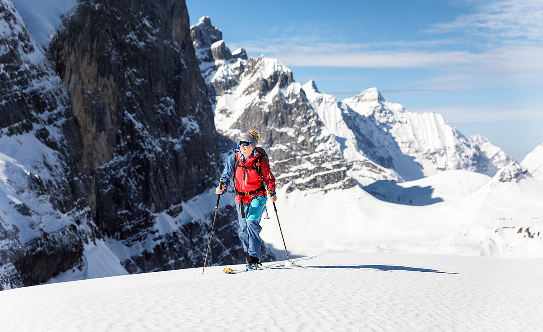 Young woman on the rise with touring skis against a mighty mountain backdrop, Karwendel, Tyrol, Austria