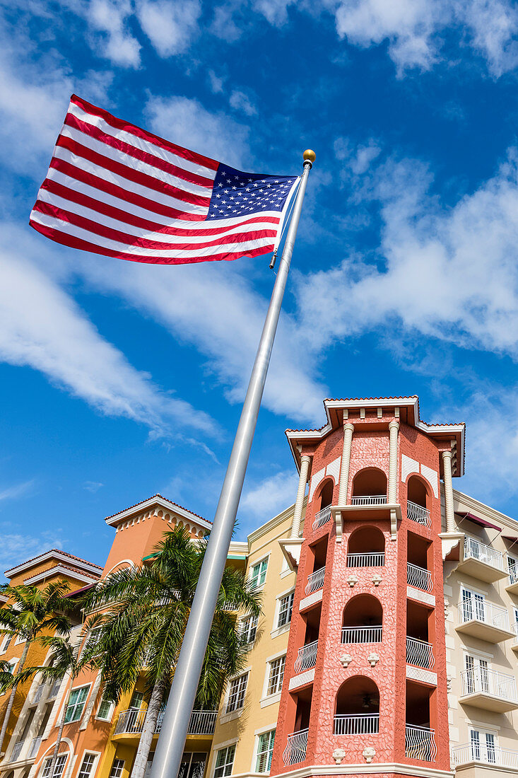 The American national flag flies in front of a colorful house facade, Naples, Florida, USA