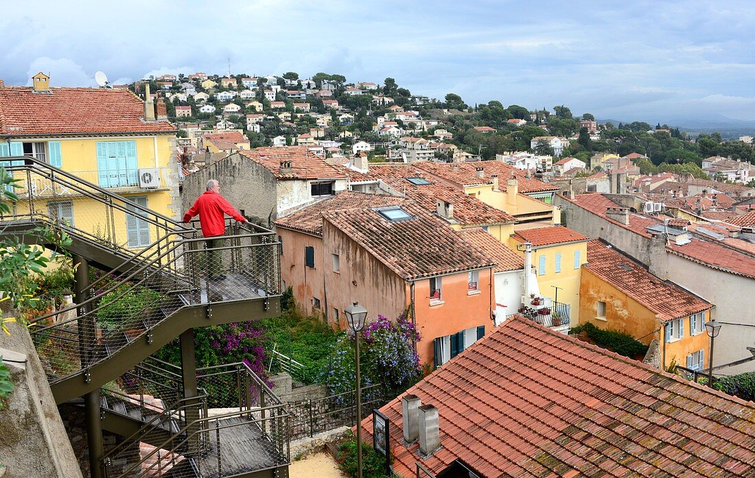 Man looks out over the rooftops of the city, on Place Saint Paul in the old town of Hyeres, Cote d'Azur, southern France