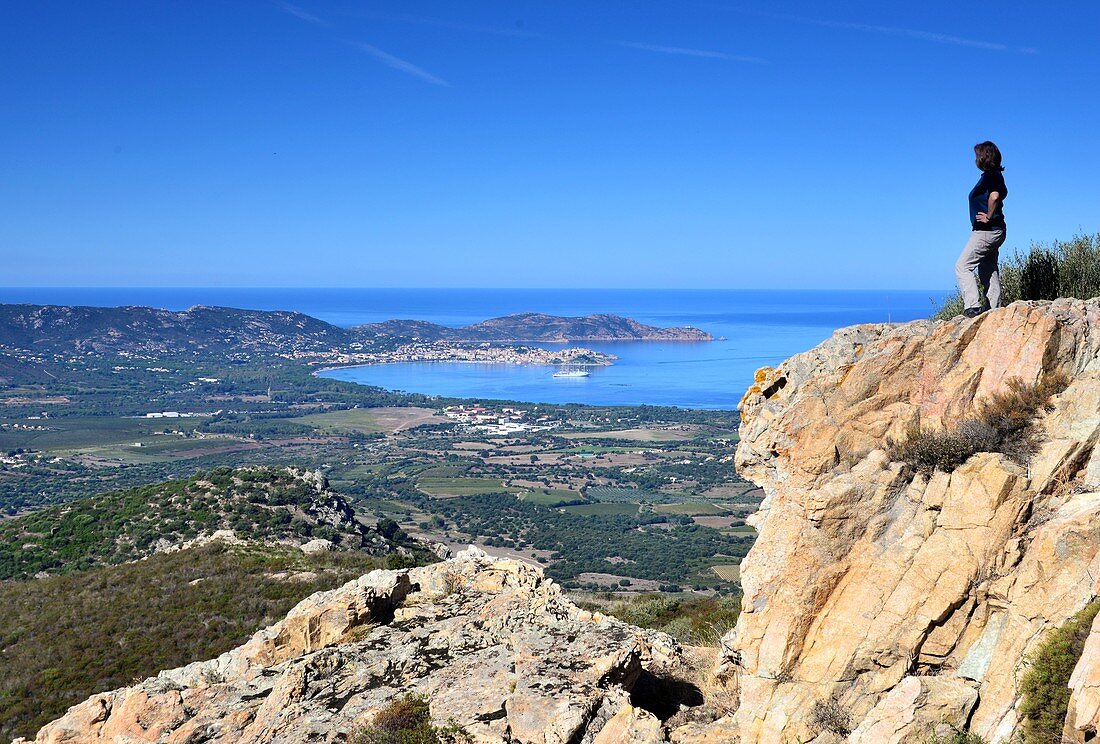 Frau schaut von Felsen auf die Bucht von Calvi, Korsika, Frankreich