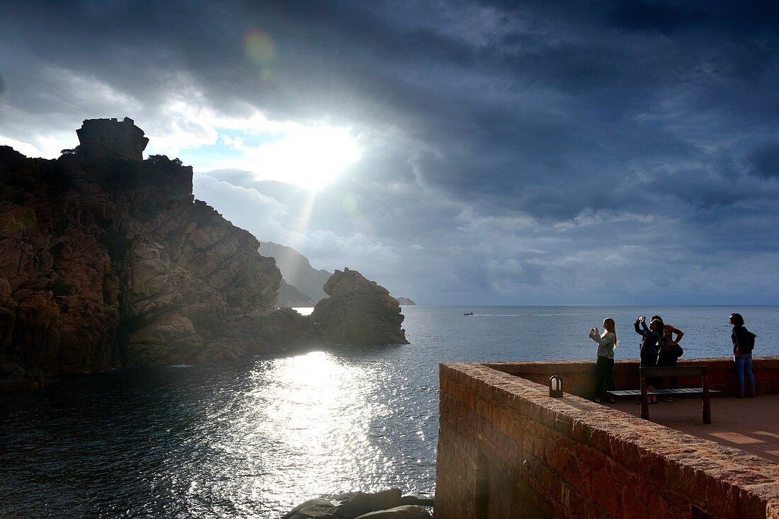 Touristen bestaunen den Sonnenuntergang bei Porto am Golf von Porto, West- Korsika, Frankreich