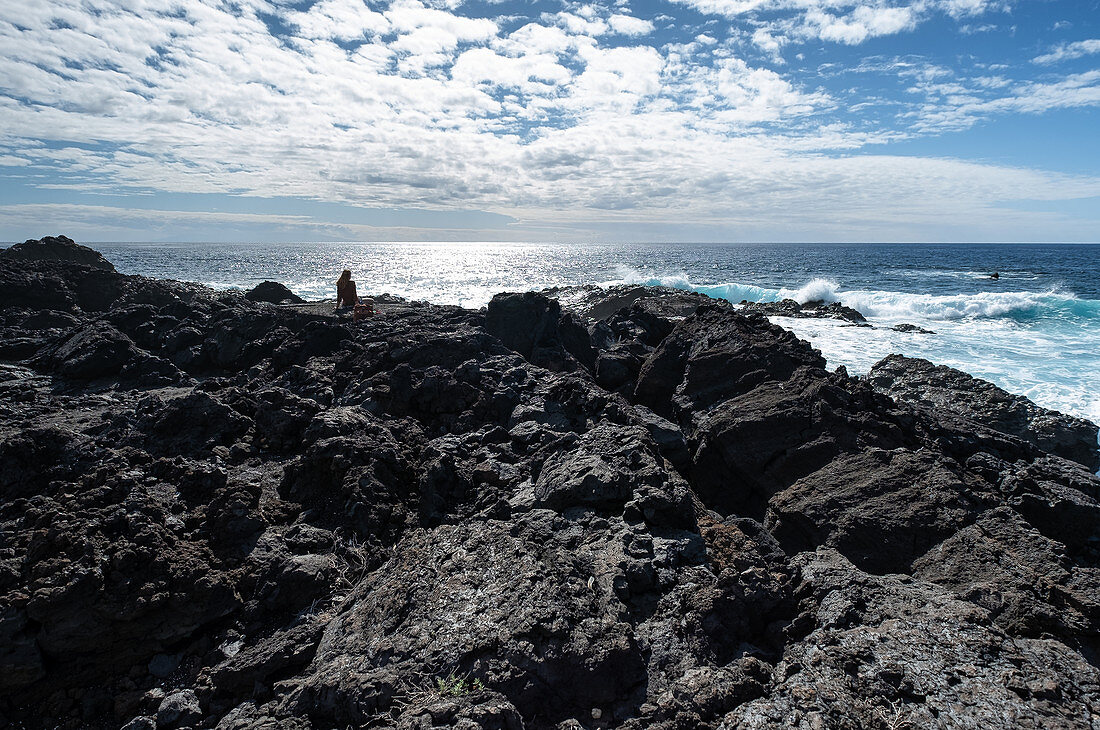 Sitzende Frau an einer Klippe bei Fuencaliente, Blick auf den Atlantik, La Palma, Kanarische Inseln, Spanien, Europa
