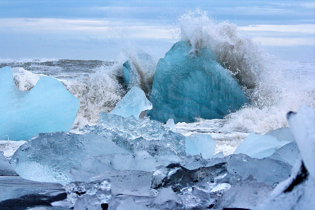 A wave breaking on the icebergs on Black Diamond Beach in southeast Iceland, Breidamerkursandur, Iceland, Europe