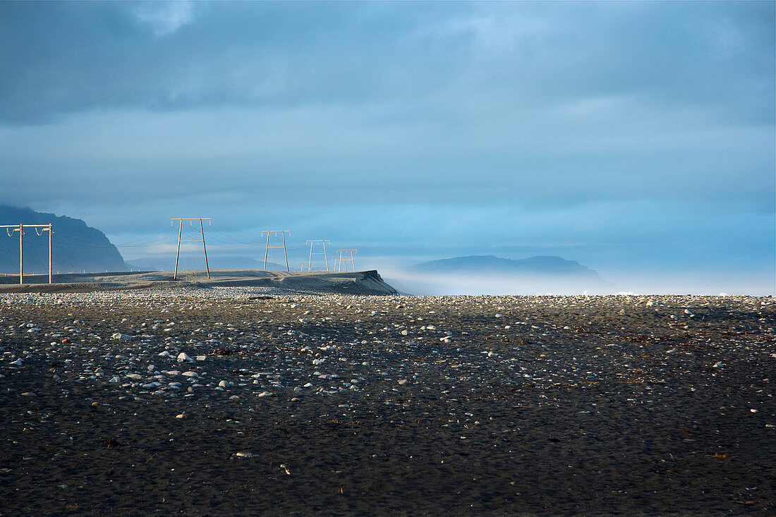 Blick auf Strommasten neben der Ringstrasse, im Vordergrund schwarzer Vulkansandstrand im Südosten Islands, Europa