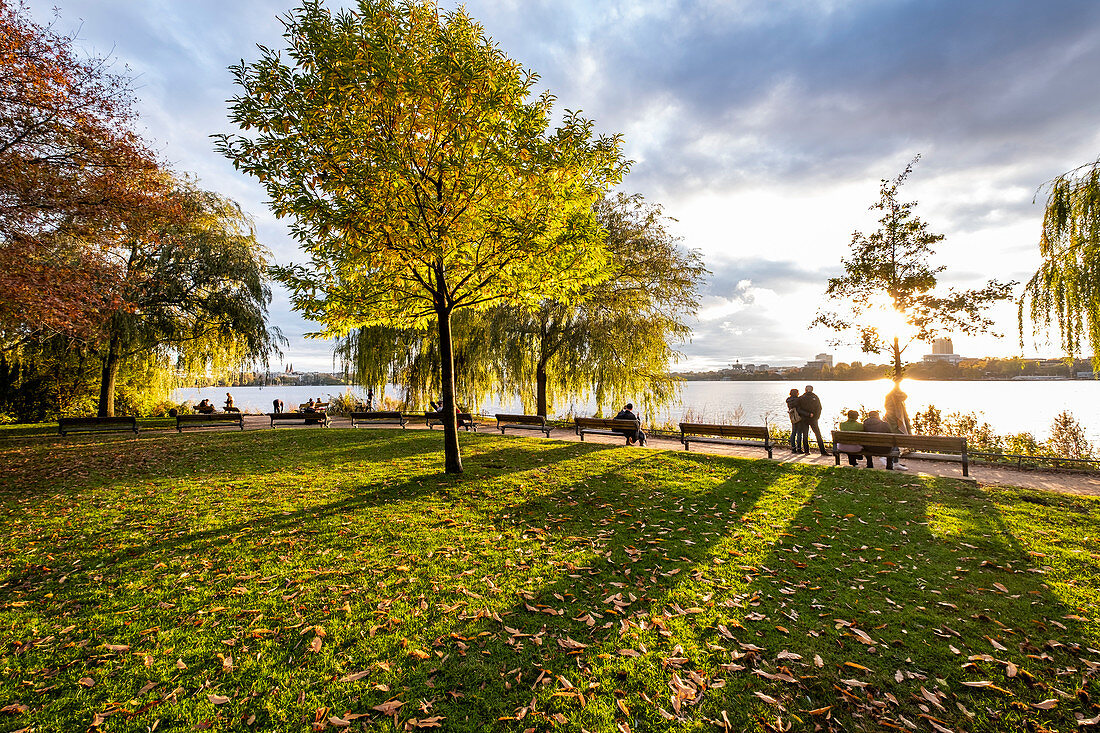 Menschen genießen den Sonnenuntergang an der Aussenalster in Hamburg, Norddeutschland, Deutschland