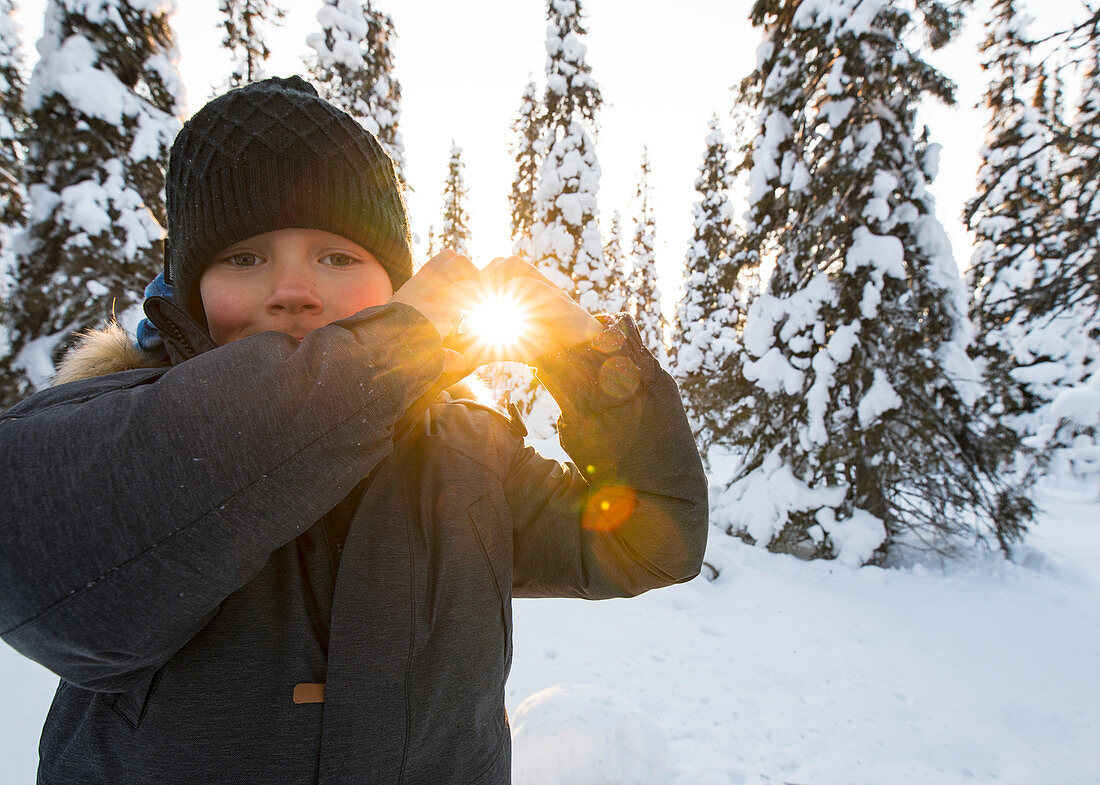 Kleiner Junge hält die Sonne in seinen Händen, Winter in Finnland