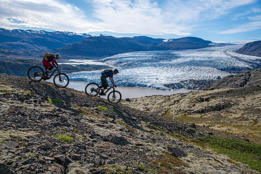 Zwei Mountainbiker fahren zu einem kleinen Gletschersee, Island
