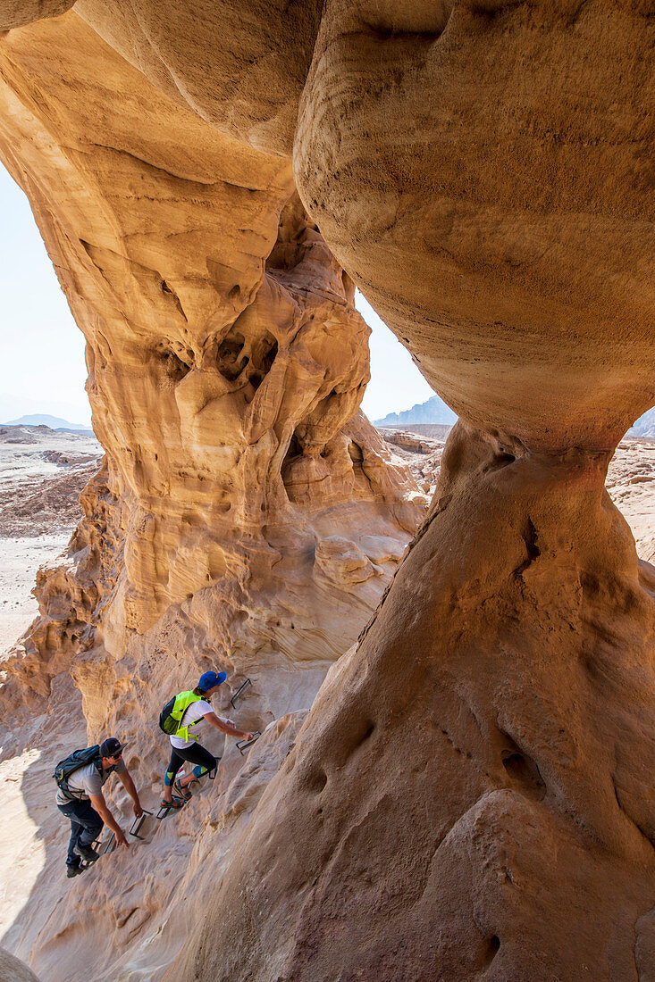 Zwei Wanderer klettern auf Felsformation in der Wüste Negev, Israel