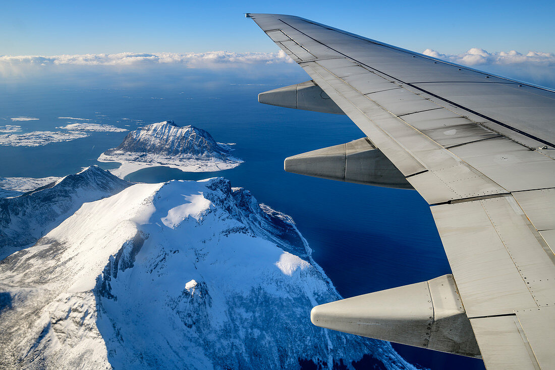 Airplane wing with snowy mountains, aerial view, near Bodö, Nordland, Norway