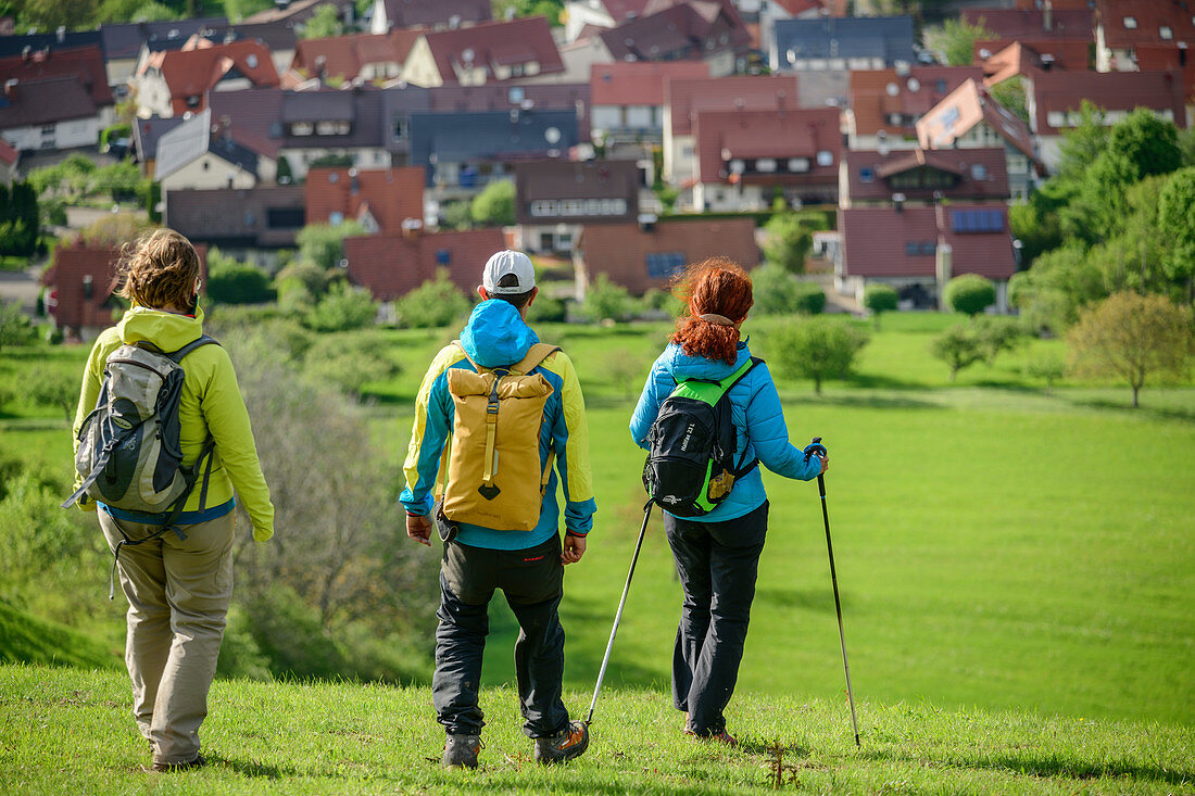 Three people hike towards Kohlberg, Jusiberg, Swabian Jura, Baden-Württemberg, Germany