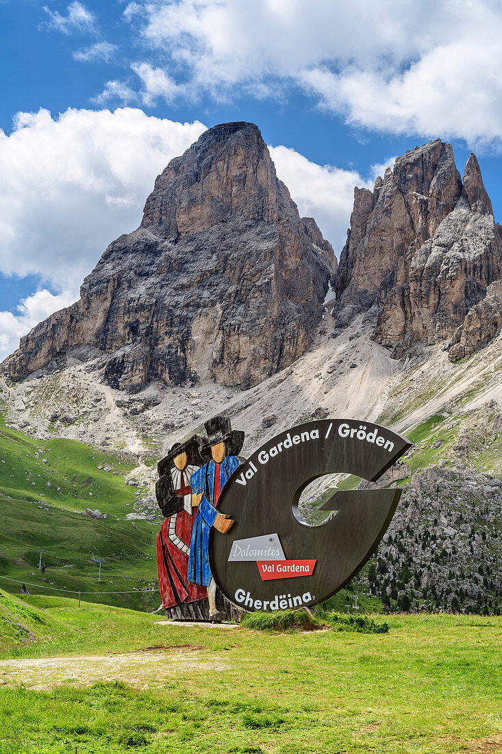 Advertising board of the Val Gardena with woman and man in traditional costume, Sassolungo in the background, Sellapass, Val Gardena, Dolomites, UNESCO World Heritage Dolomites, South Tyrol, Italy