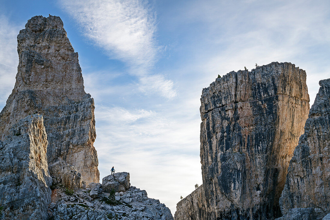 Person stands on boulder between Cinque Torri, Cinque Torri, Dolomites, UNESCO World Heritage Dolomites, Veneto, Italy
