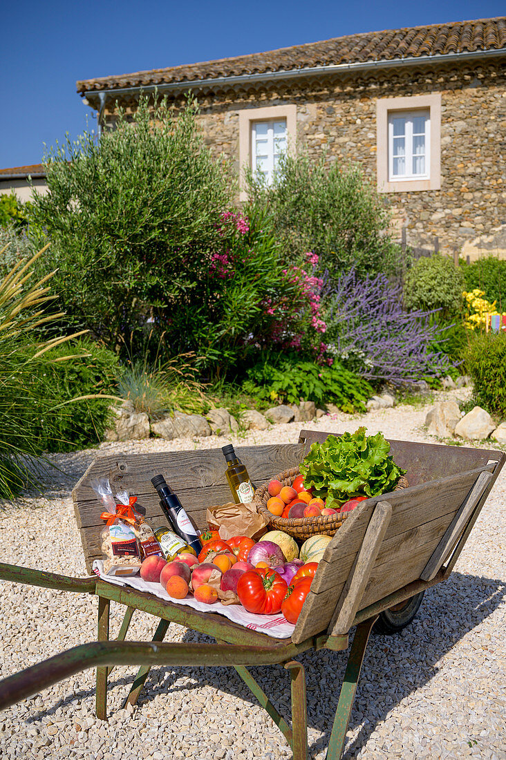 Frische Einkäufe wie Obst und Gemüse in einem Garten vor Steinhaus, Frankreich