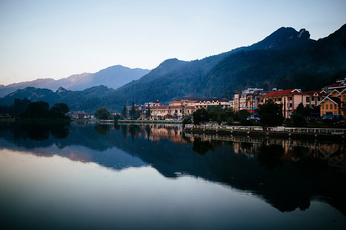 Buildings and mountains reflected in a small lake.