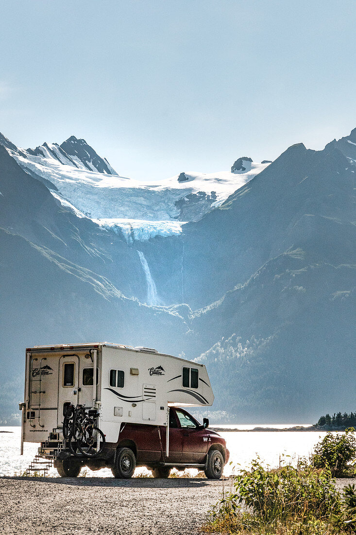 Camper, motorhome pauses on the coast in Haines, Alaska. Glacier is melting in the background