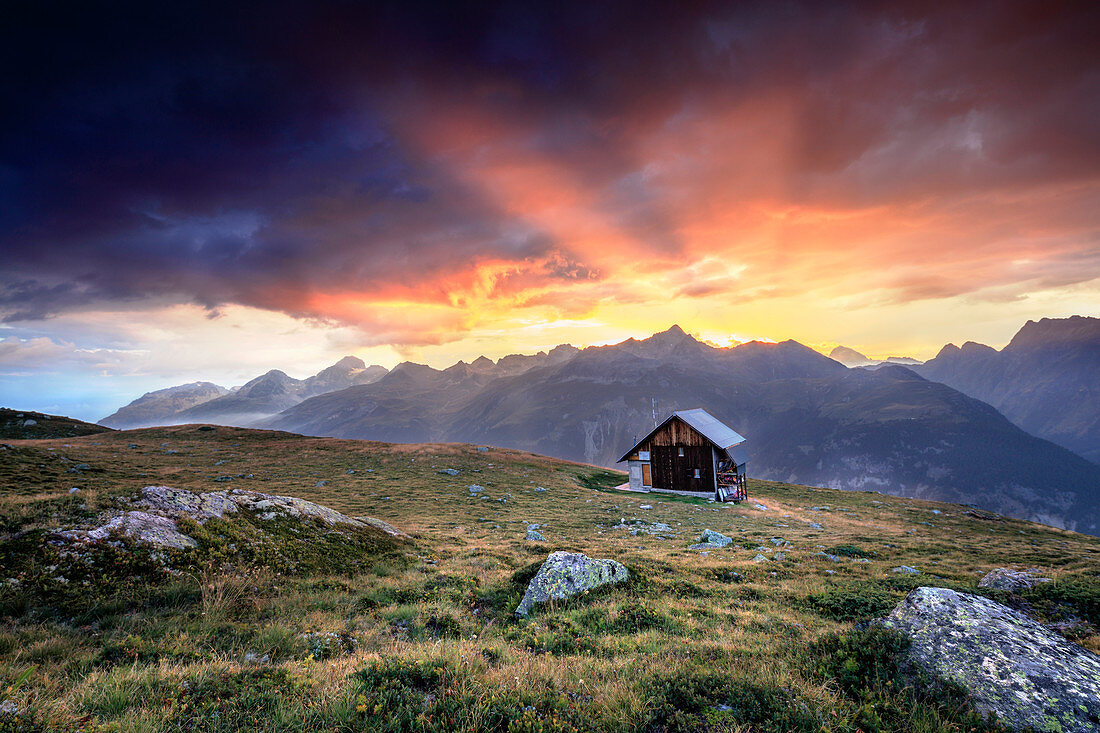 Holzhütte unter feurigem Himmel und Wolken bei Sonnenuntergang, Muottas Muragl, St. Moritz, Kanton Graubunden, Engadin, Schweiz, Europa