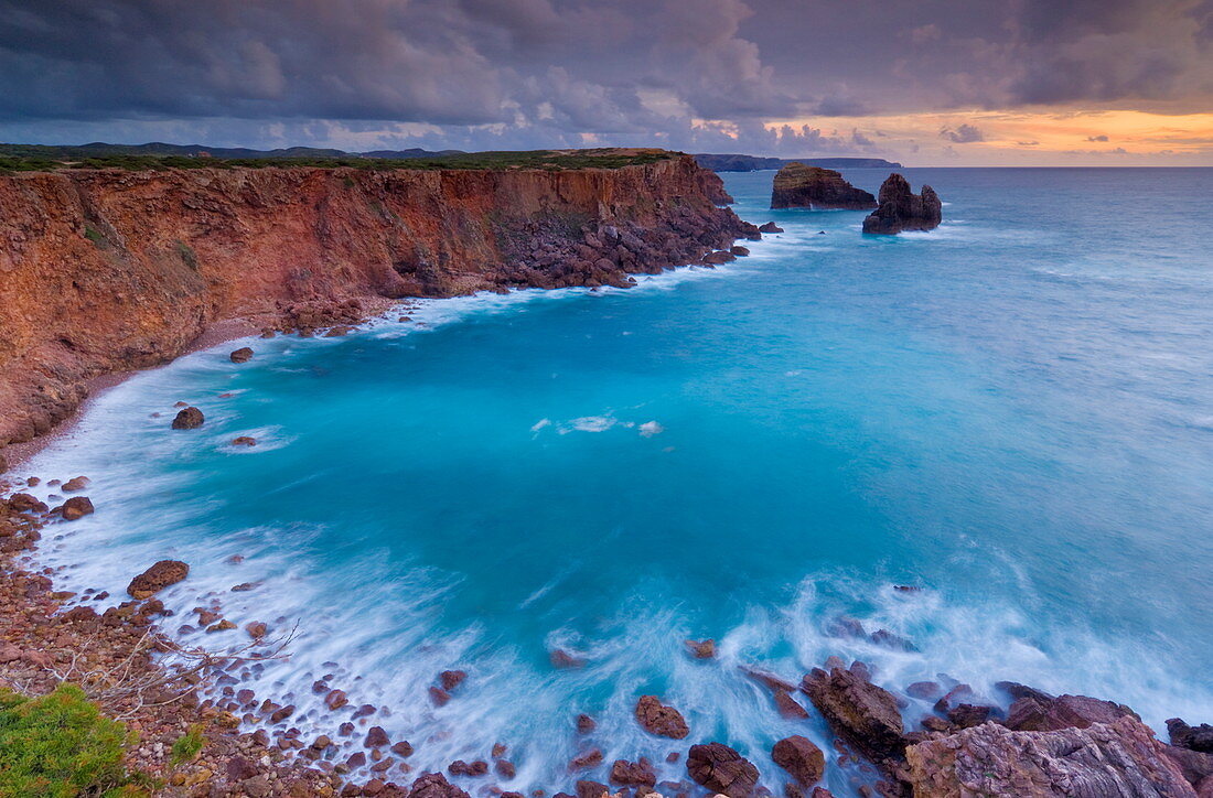 Stürmischer Himmel beim Sonnenuntergang mit milchiger Flut und Brandung, Costa Vincente, Atlantikküste der Algarve, Portugal