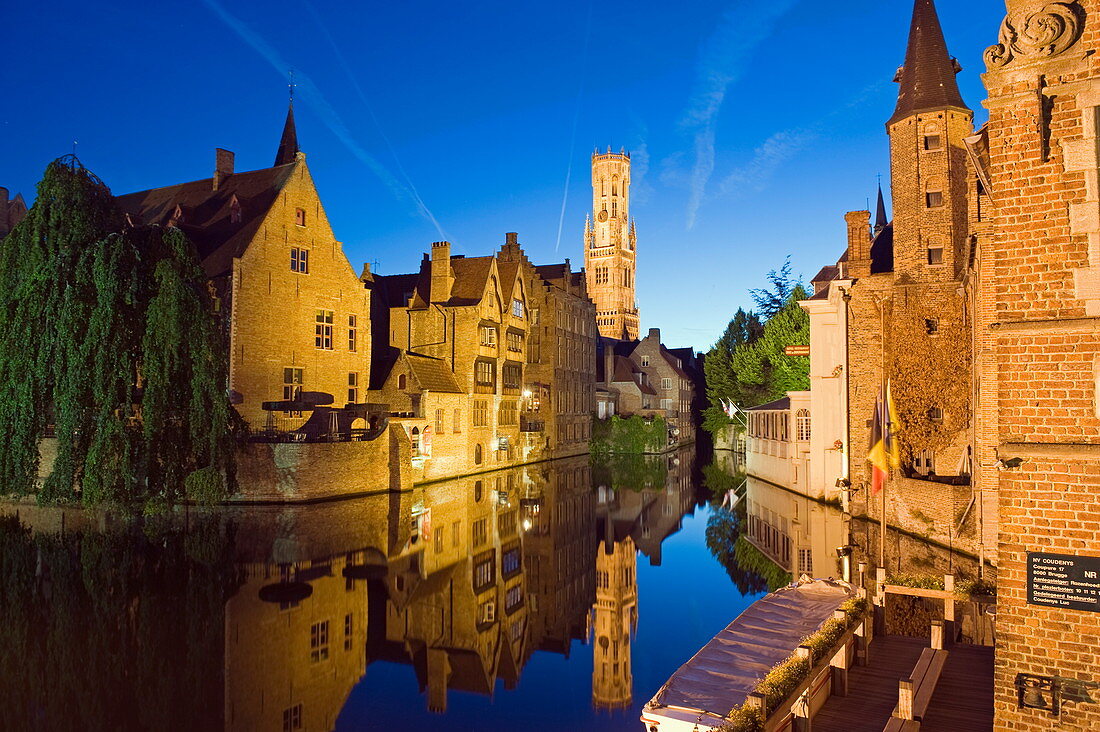 Reflection in canal of Belfort (belfry tower) illuminated at night, Old Town, UNESCO World Heritage Site, Bruges, Flanders, Belgium, Europe