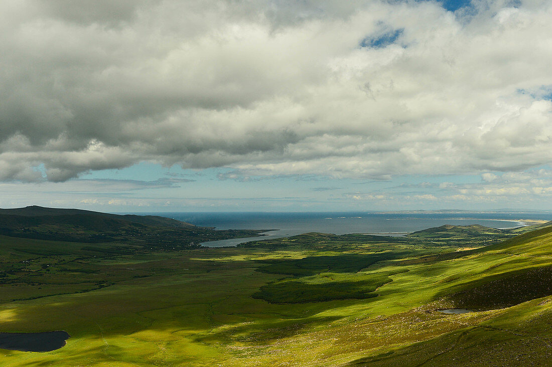 Blick über die Hügel auf den Atlantik am Connor Pass, Dingle-Halbinsel, County Kerry, Irland