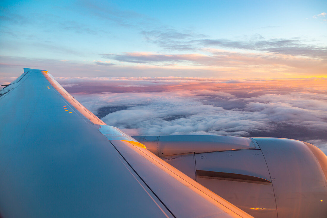 Blick aus dem Flugzeugfenster auf den Flugzeugflügel und Sonnenaufgang über England, Vereinigtes Königreich, Europa