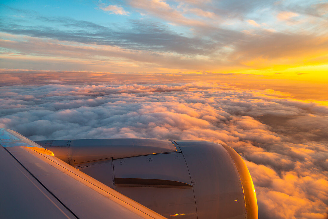 Blick aus dem Flugzeugfenster auf den Flugzeugflügel und Sonnenaufgang über England, Vereinigtes Königreich, Europa