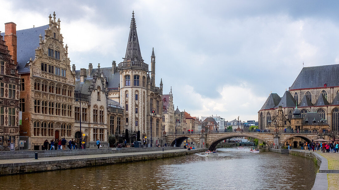 Einheimische und Besucher entspannen sich entlang des Leie-Kanals, der für seine wunderschönen historischen Fassaden bekannt ist, Graslei, Gent, Belgien, Europa