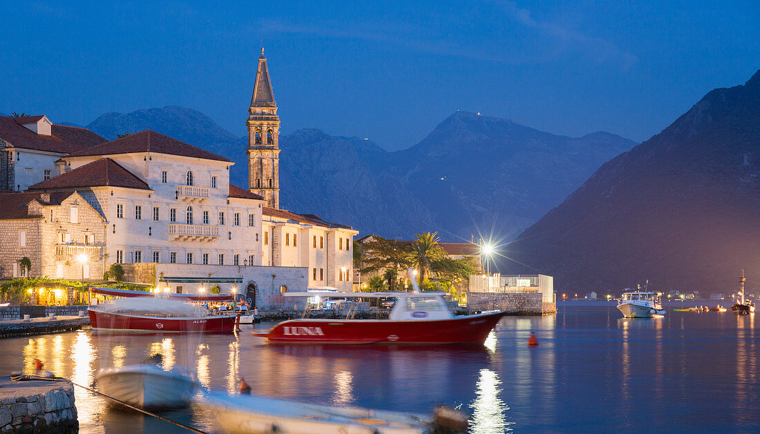 View across the illuminated harbour to waterfont mansions overlooking the Bay of Kotor, dusk, Perast, Kotor, UNESCO World Heritage Site, Montenegro, Europe