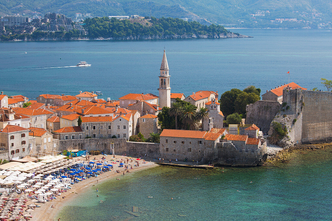 Blick über den überfüllten Strand in die Altstadt (Stari Grad) und zur Budva Bay, Budva, Montenegro, Europa